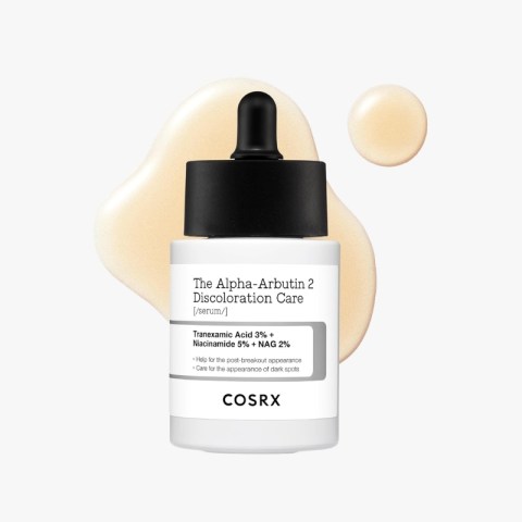 Bottle of COSRX The Alpha-Arbutin 2 Discoloration Care serum with dropper, label visible and beige serum splatter behind it