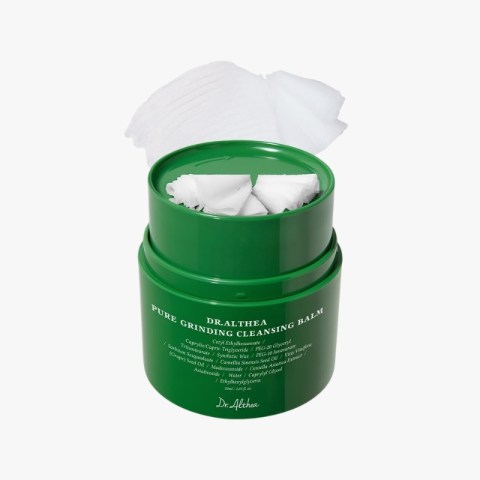 Green jar of Dr. Althea Pure Grinding Cleansing Balm with a tissue pulled from the lid, ready for use.