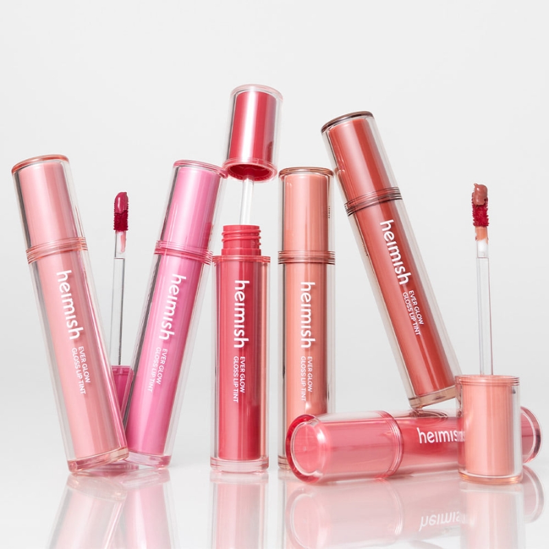 Set of pink lip gloss tubes with applicators, arranged upright on a white surface.